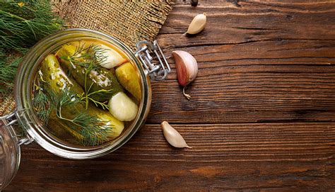 برطمان مخلل خيار مع شبت وثوم على طاولة خشبية